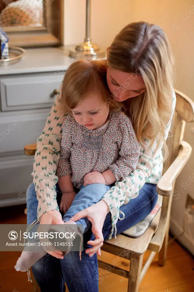 Mother helping daughter put on shoe