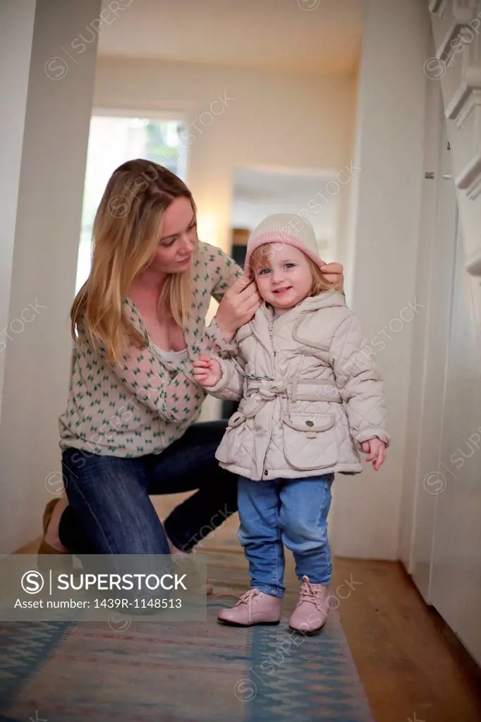 Mother putting knit hat on daughter