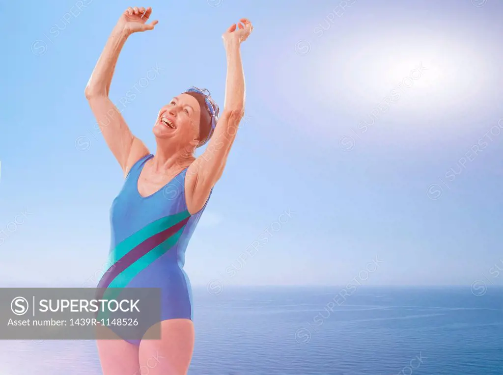 Senior woman wearing swimsuit cheering with arms raised