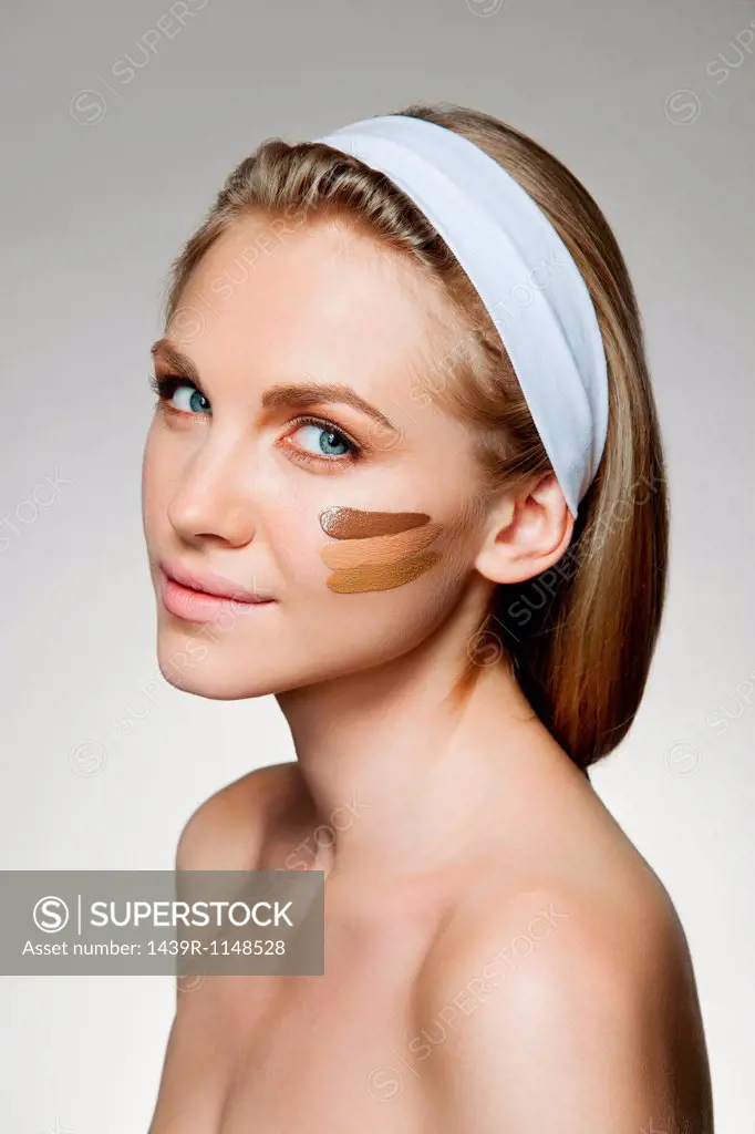 Woman with stripes of foundation on cheek