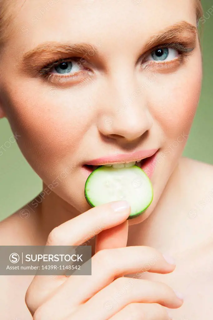 Woman biting piece of cucumber