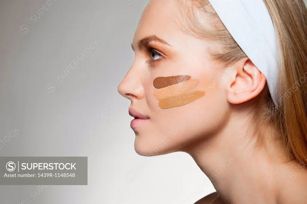 Woman with stripes of foundation on cheek