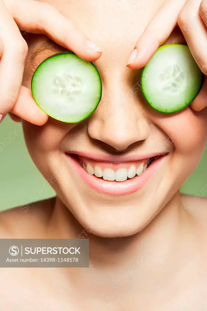 Woman covering eyes with cucumber