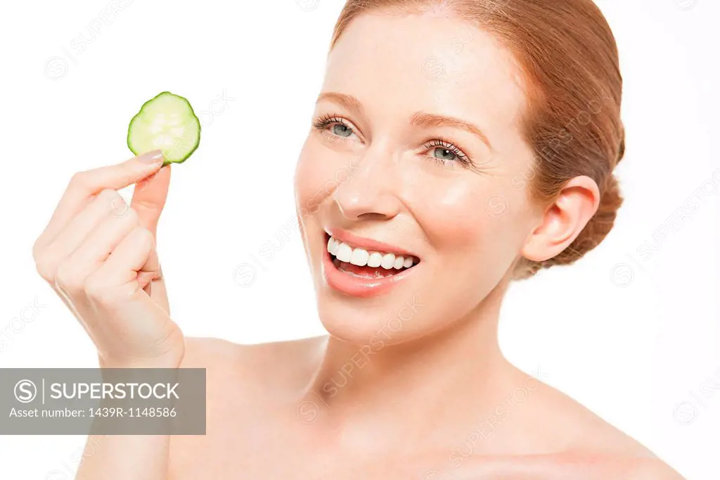 Woman holding up a cucumber slice