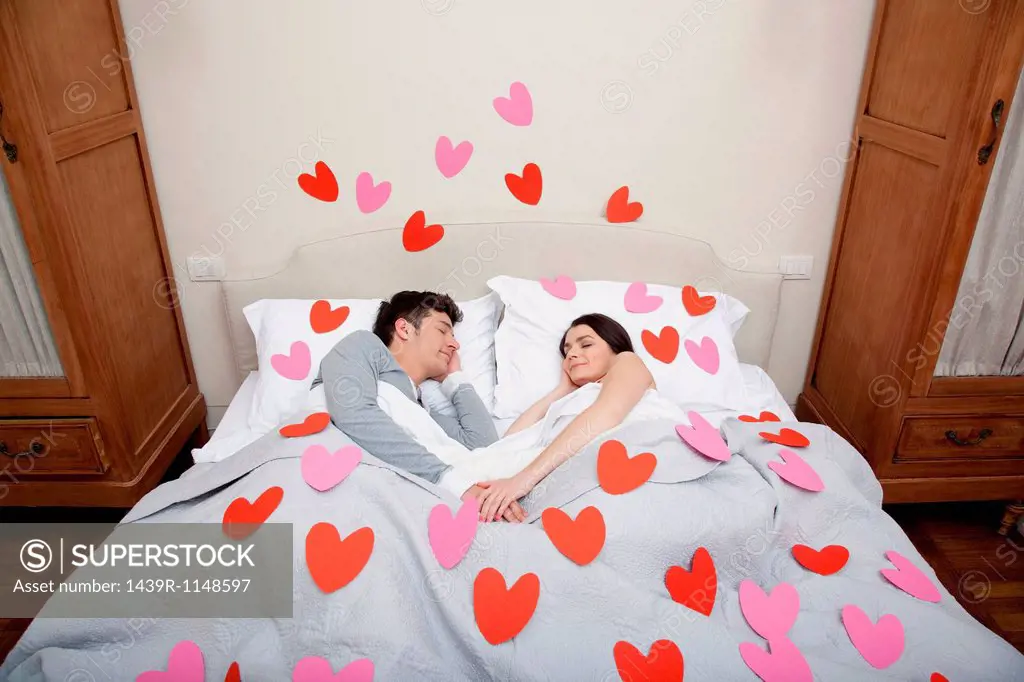 Couple in bed with heart shapes on bedclothes