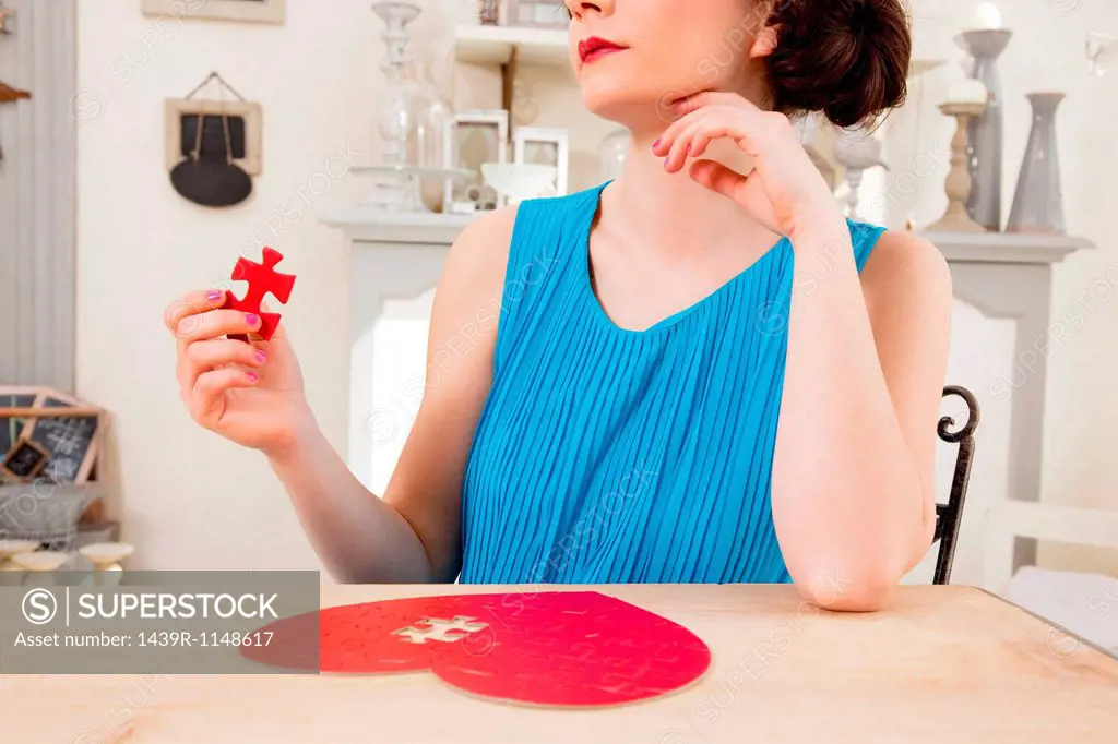Woman doing heart shaped jigsaw puzzle holding piece
