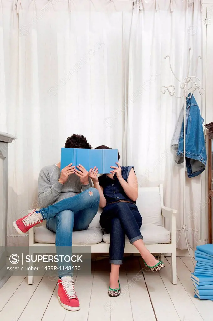 Couple hiding behind books