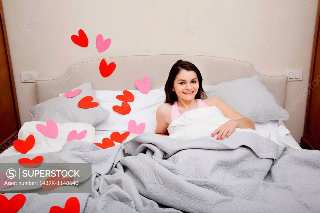 Woman in bed with heart shapes on bedclothes