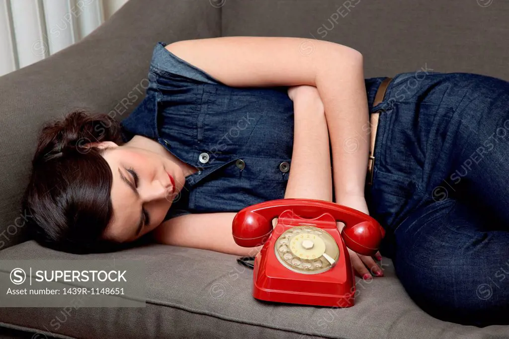 Woman lying on sofa with telephone