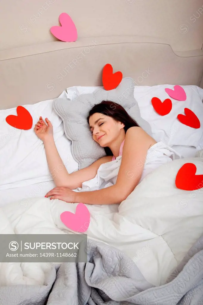 Woman in bed with heart shapes on bedclothes