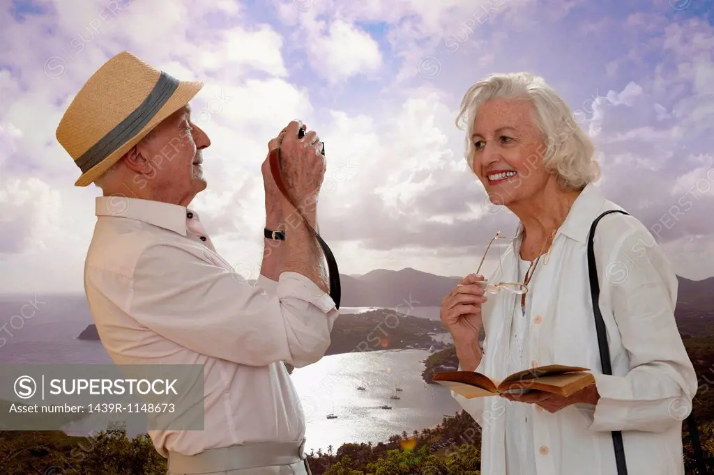 Senior man photographing wife by the sea