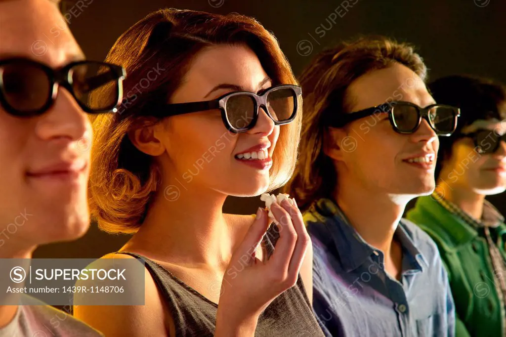 Row of people watching 3D movie, woman with popcorn