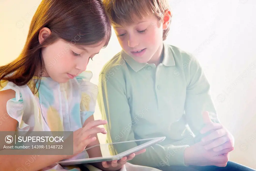 Girl and boy using digital tablet with bright light