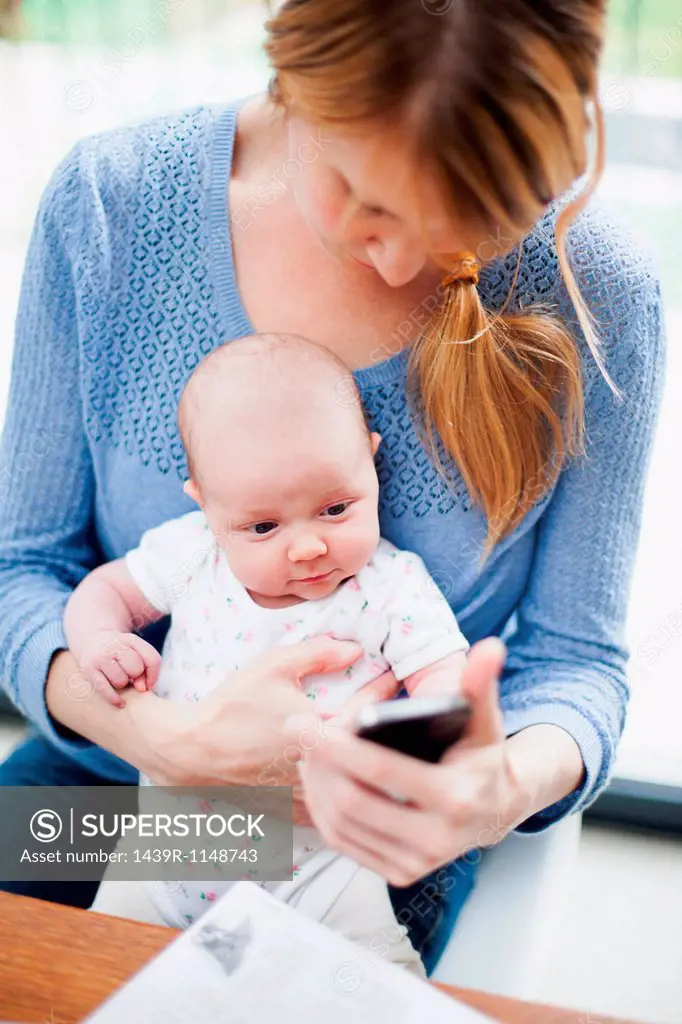 Mother with newborn baby and cell phone
