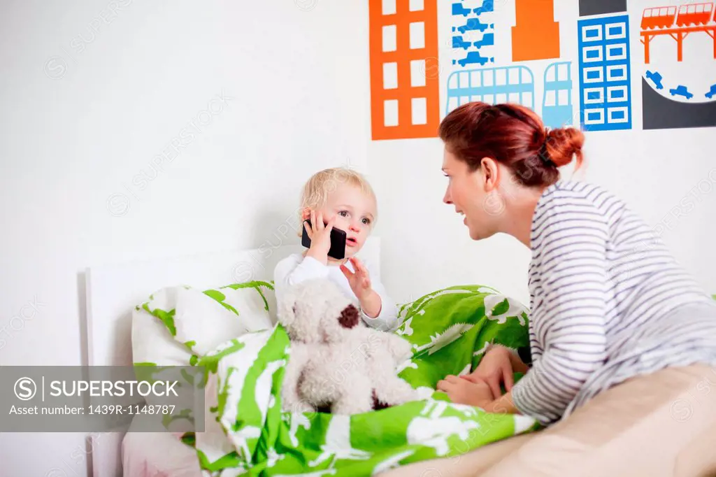 Mother with son in bed on cell phone