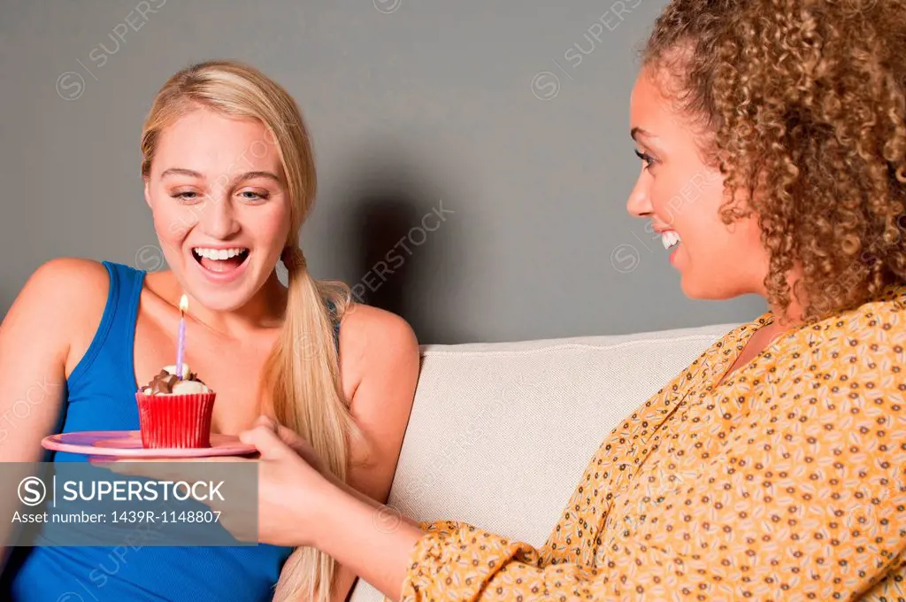 Woman giving friend cupcake