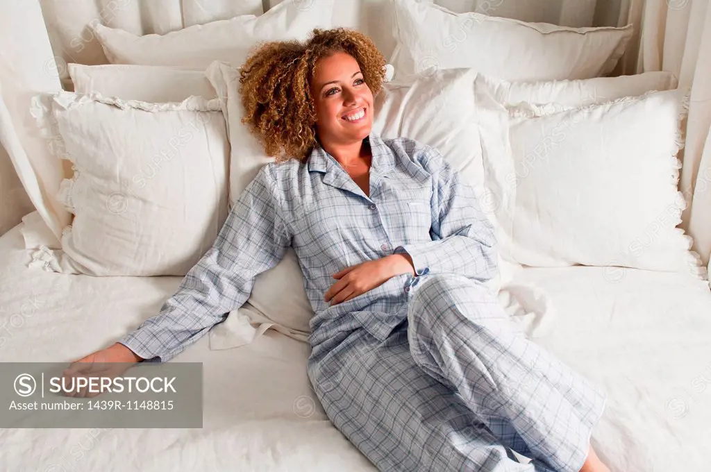 Woman wearing pyjamas reclining in bed