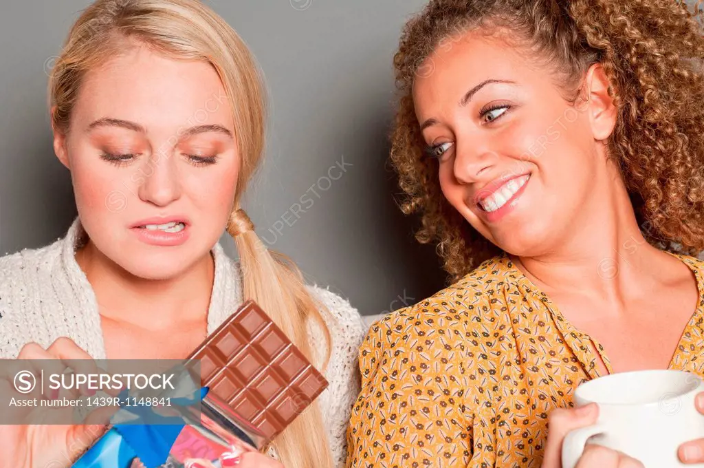 Woman staring at friend holding chocolate