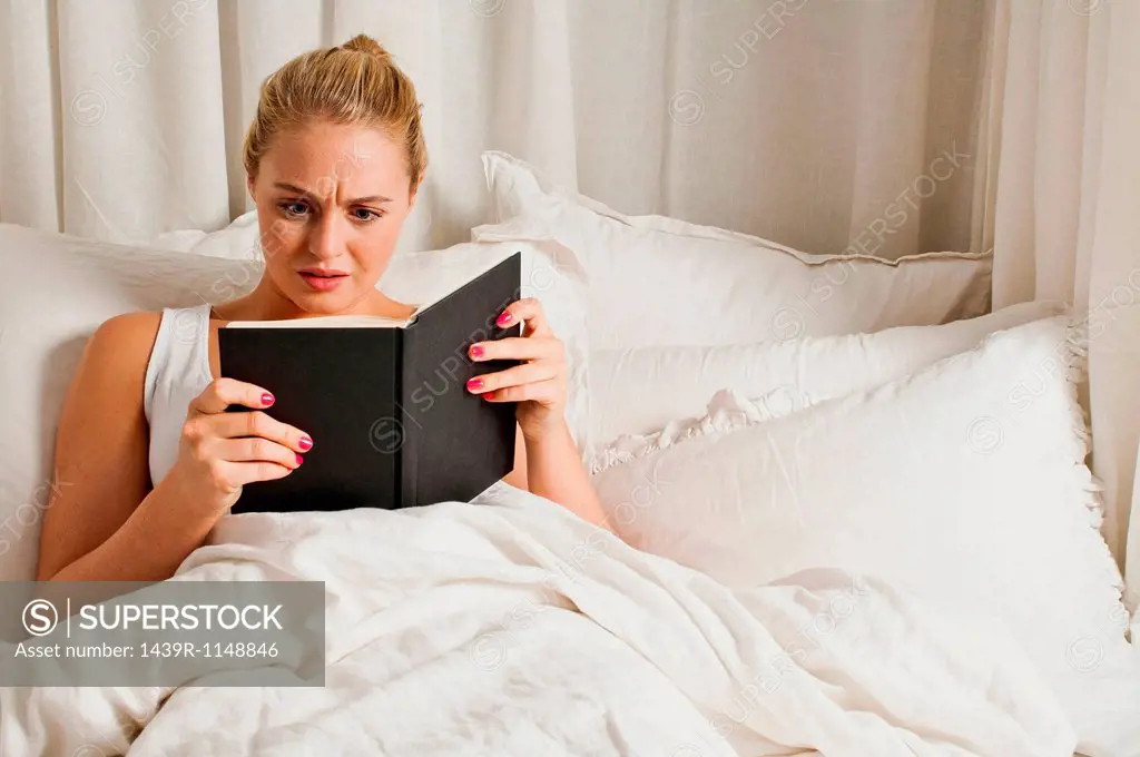 Woman reading book in bed