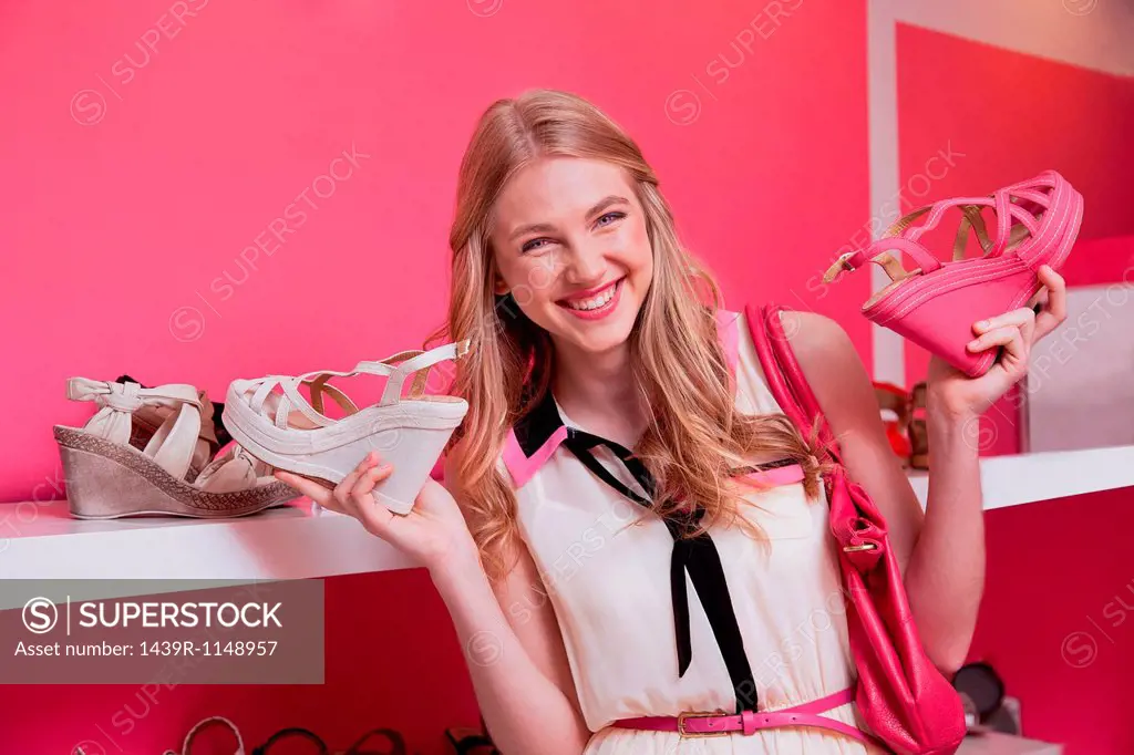 Happy young woman holding shoes in store