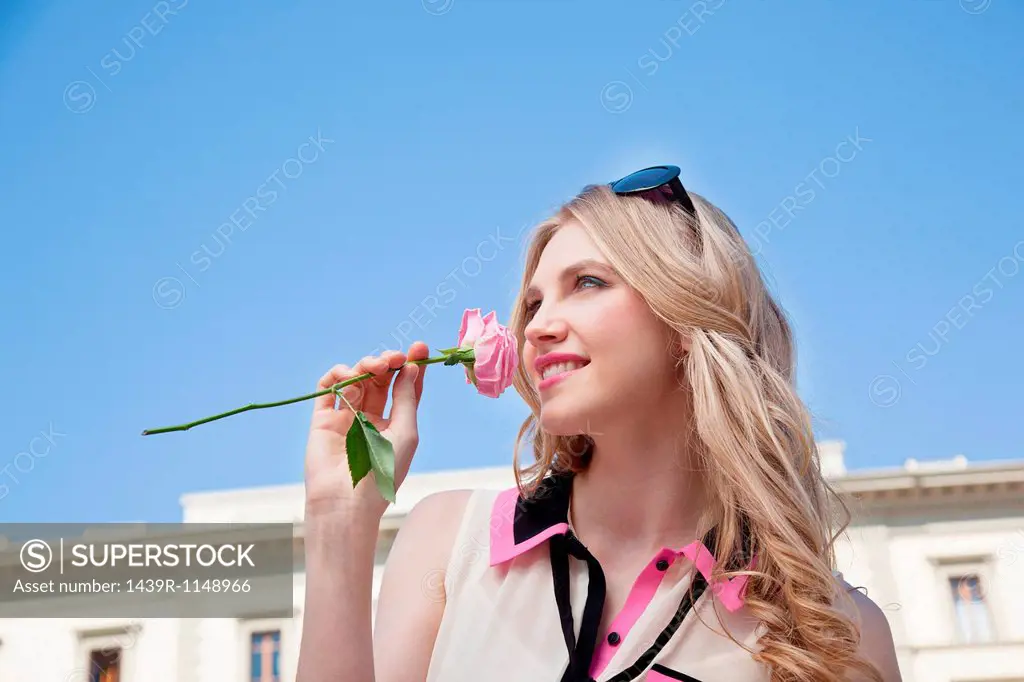 Young woman outdoors smelling rose