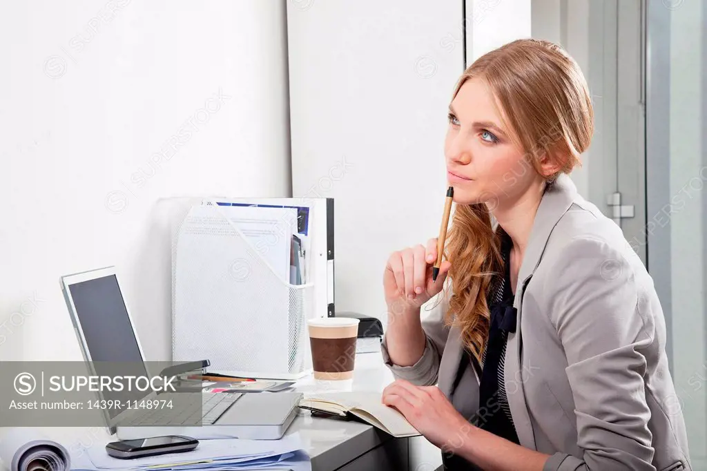 Young woman at her desk, thinking