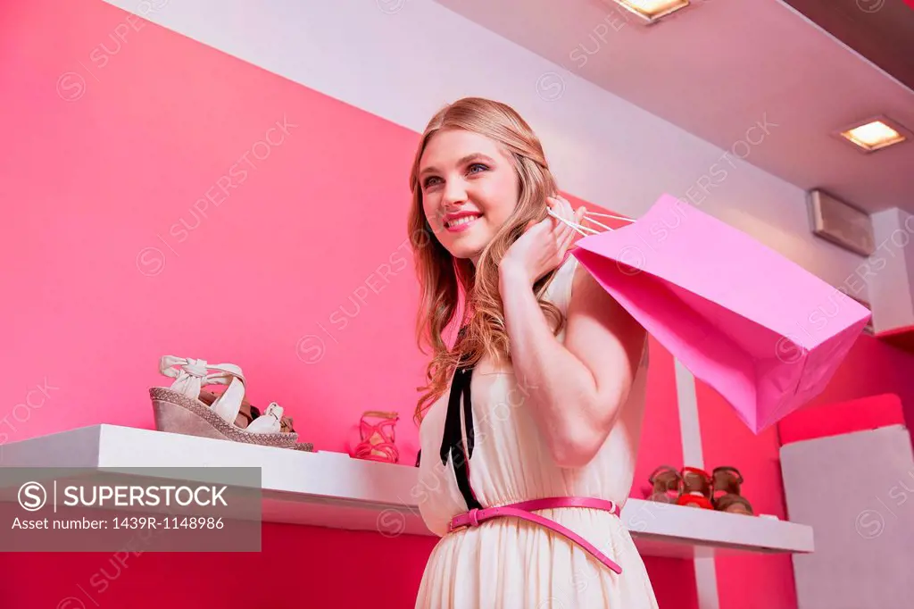Young woman in shoe store with shopping bag