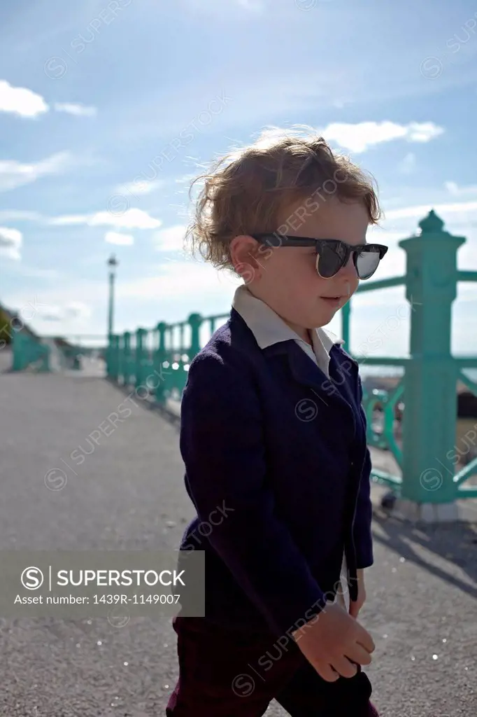 Little boy on promenade, wearing mod style clothing with sunglasses