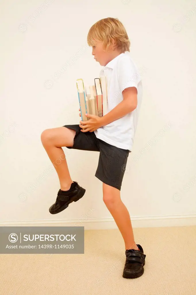 Schoolboy carrying stack of school books