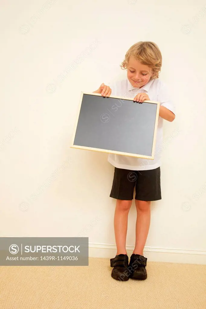 Schoolboy holding blank blackboard