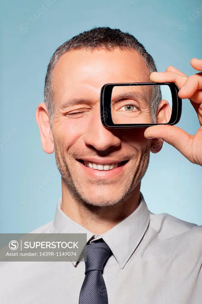 Man with smartphone over eye