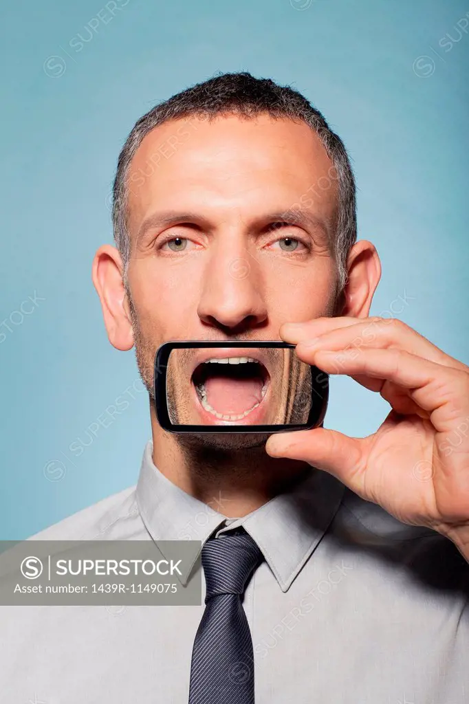 Man with smartphone over mouth