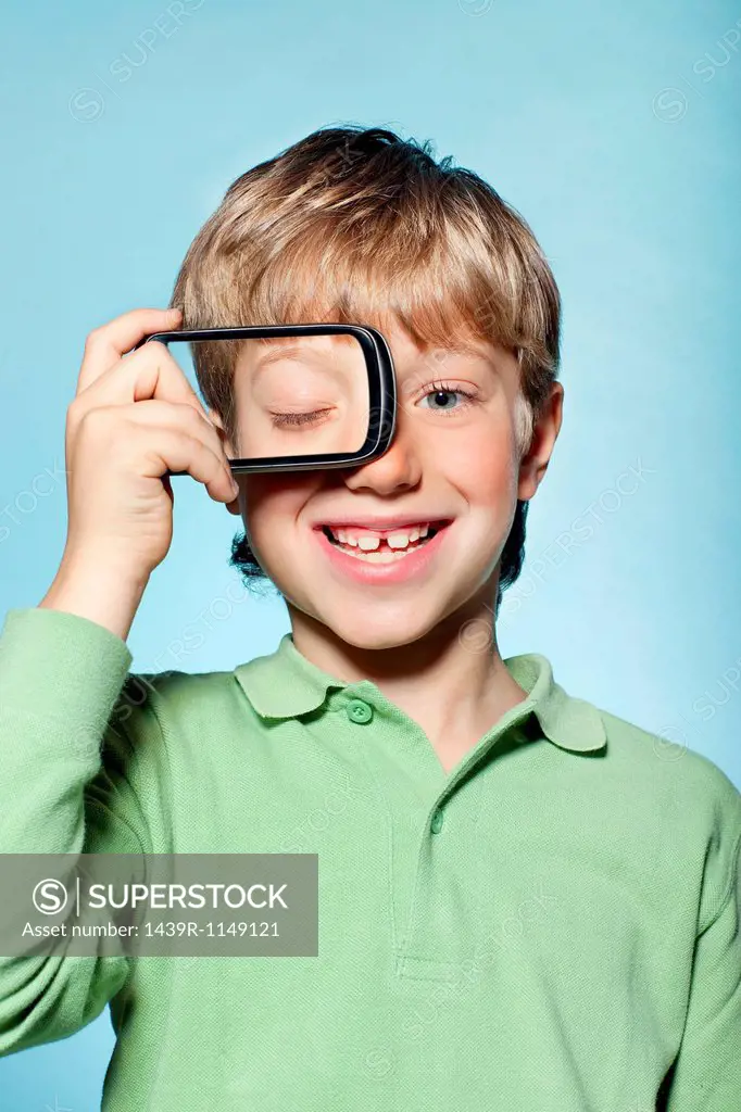 Boy holding smartphone over eye