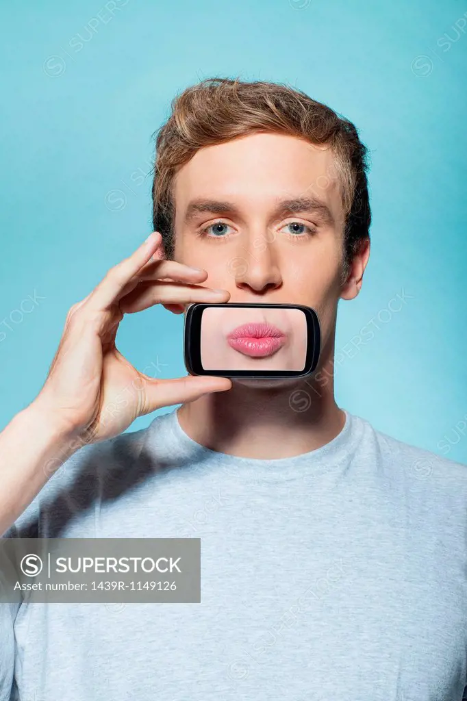 Man holding smartphone over mouth