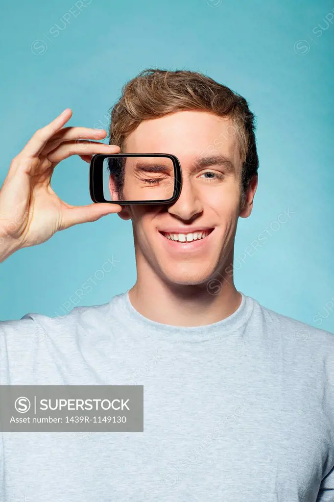 Man holding smartphone over eye