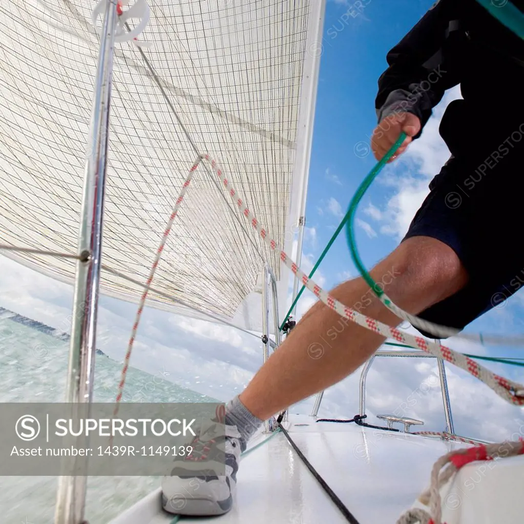 Man on yacht, pulling ropes