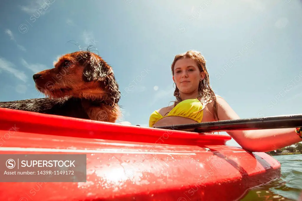 Teenage girl and pet dog in kayak