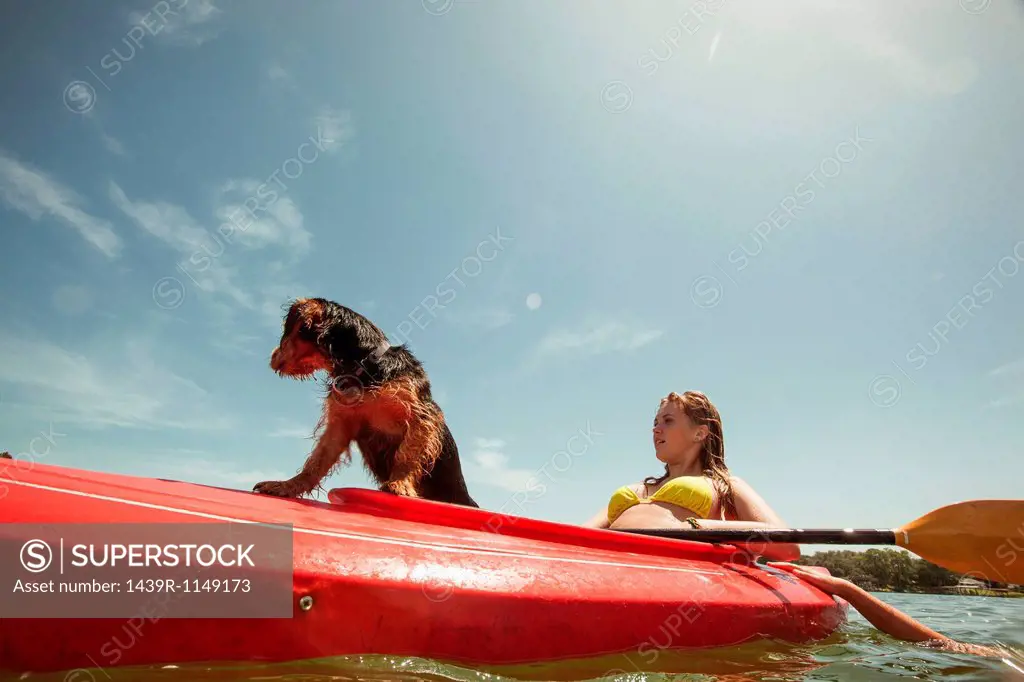 Teenage girl and pet dog in kayak