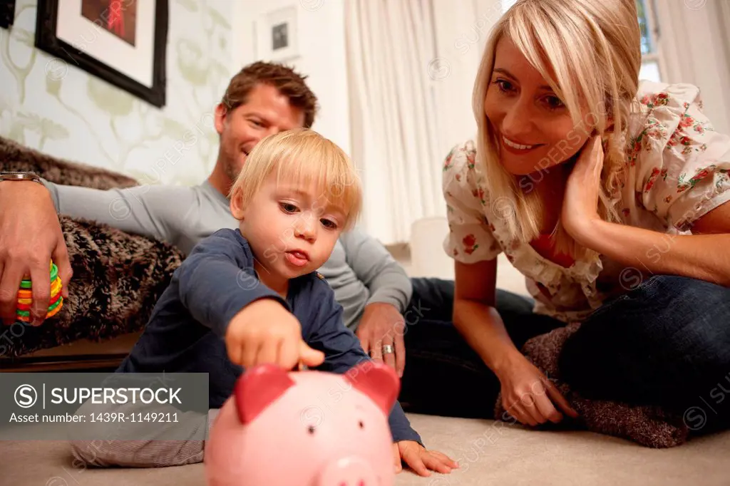 Father, mother and son putting coins in piggy bank