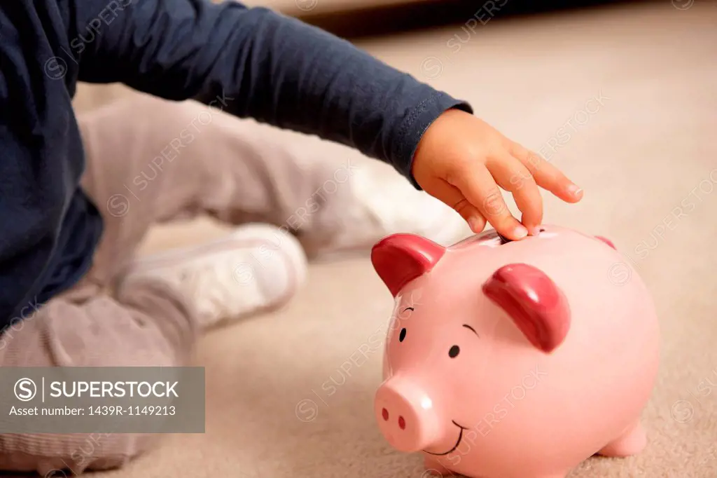 Close up of boy putting coins in piggy bank