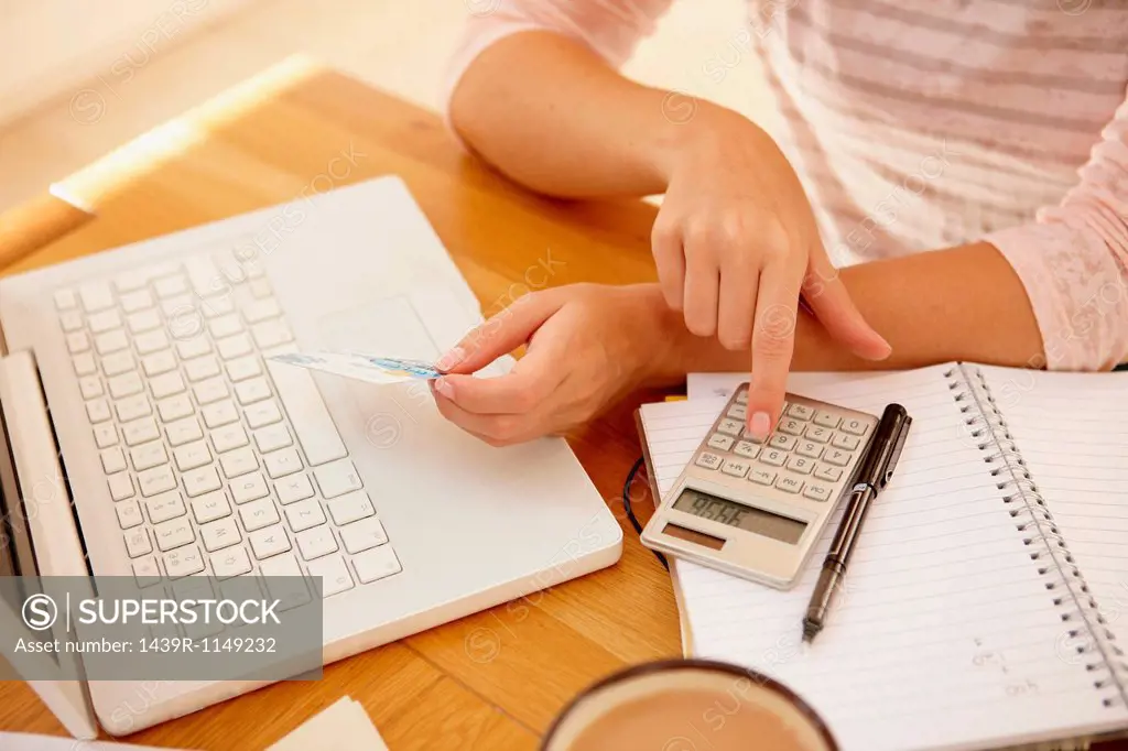 Woman using calculator with laptop