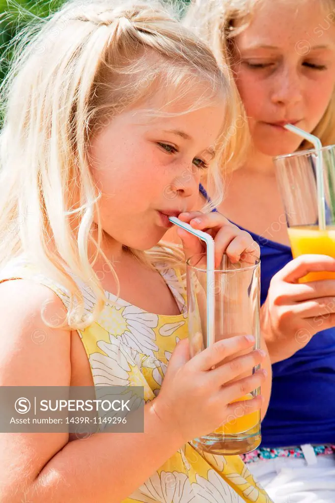 Two girls drinking orange juice