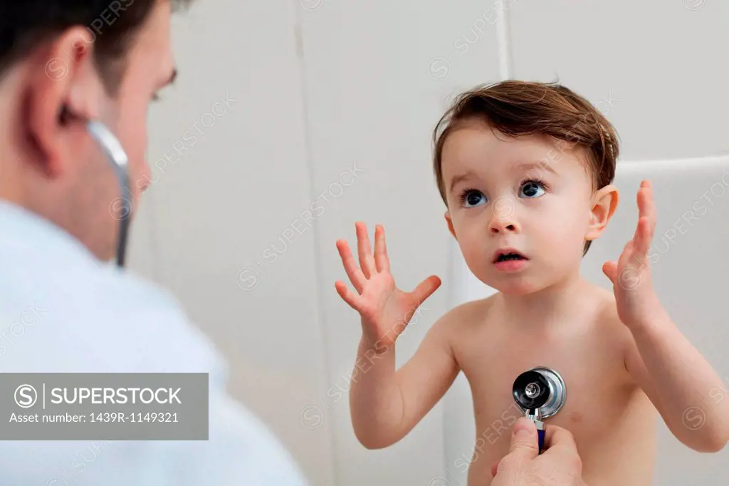 Doctor using stethoscope to check little boy