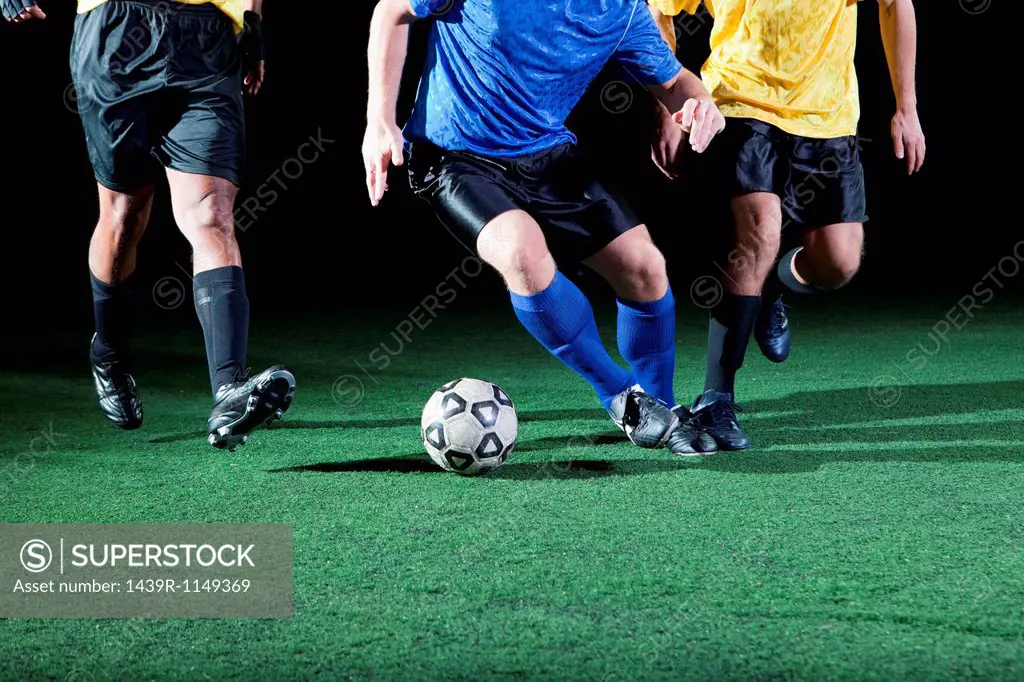 Soccer players tackling on pitch, low section