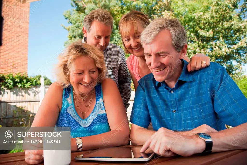 Senior and mature friends looking at digital tablet outdoors
