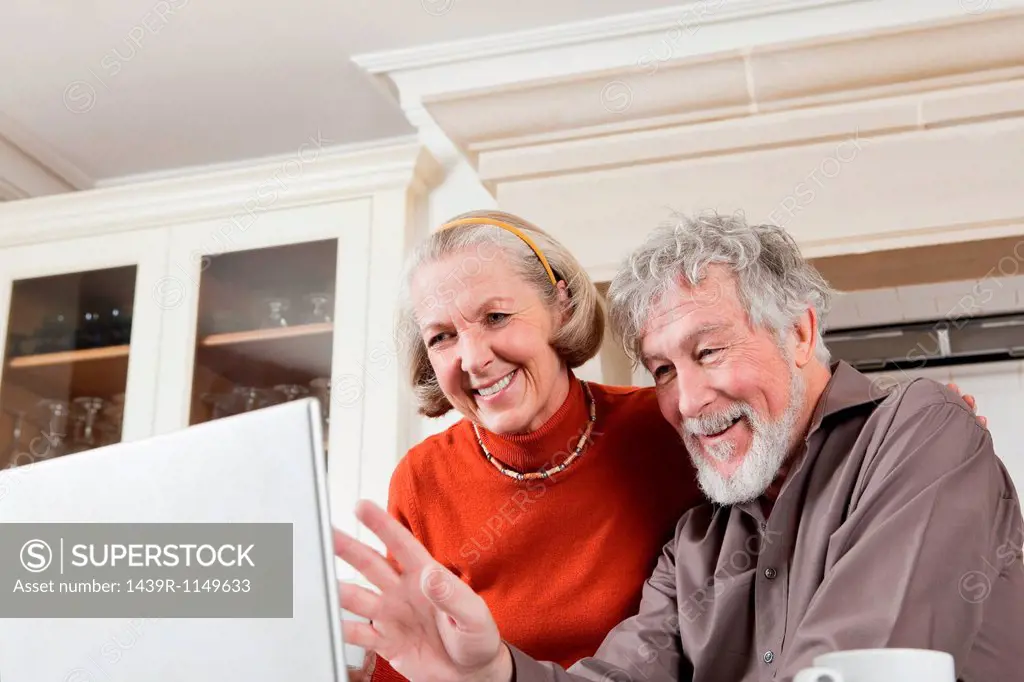 Senior couple using webcam on laptop