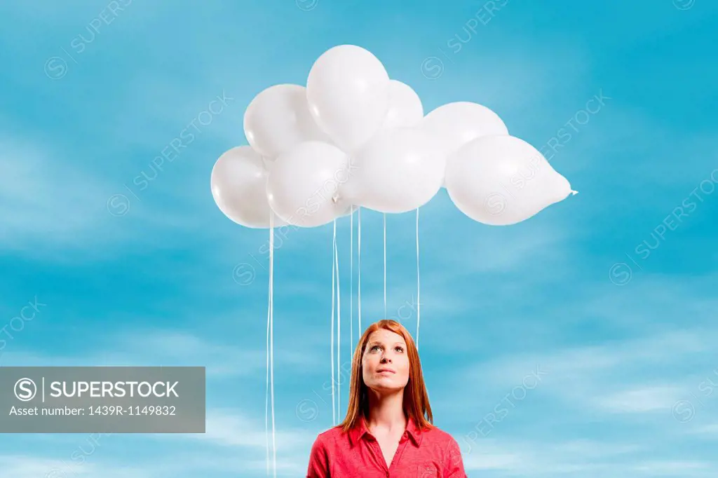 Young woman looking at thought bubble made of balloons