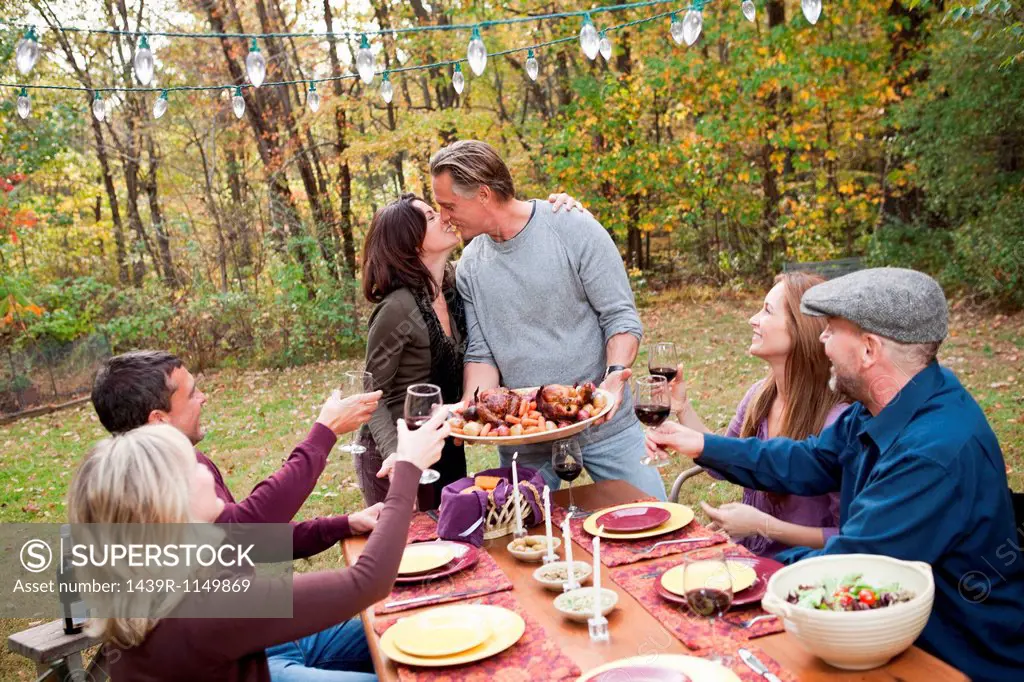 Couple kissing at outdoor dinner with friends