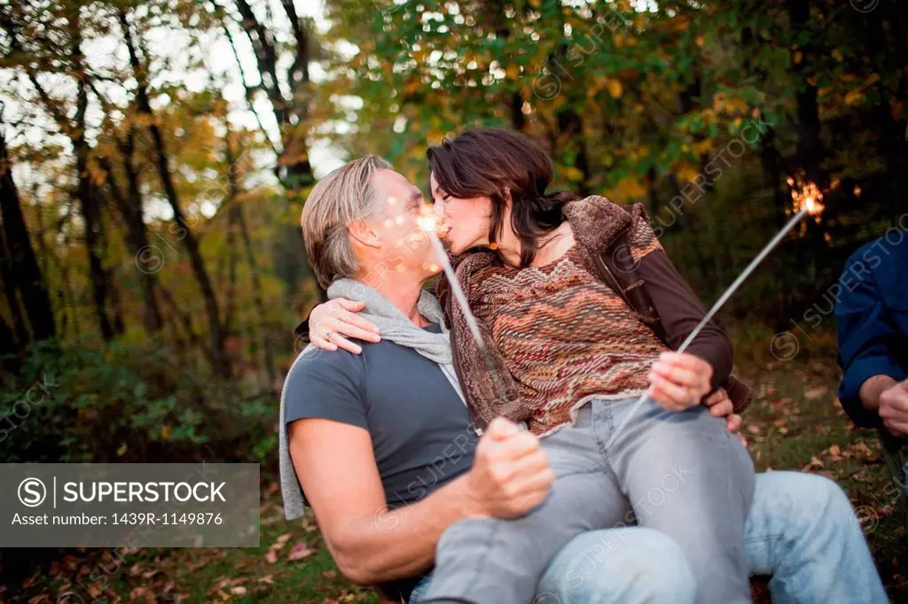 Mature couple kissing with sparklers