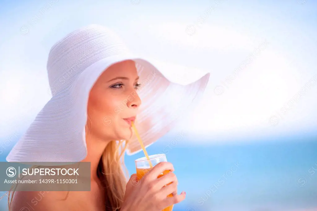 Woman in floppy hat drinking juice